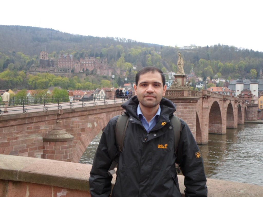Dr. Mahdi Kohandani auf der Alten Brücke in Heidelberg; dahinter der Neckar, die Altstadt und das Schloss am Hang